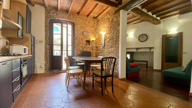 A rustic kitchen with a dining area, stone walls, and a fireplace. - Panicale 7 - Three Bedroom Apartment, Sleeps 6 (Firenze)