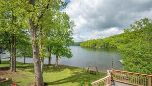 A lakeside view with a wooden deck, a swing, and a boat dock. - Cozy Dog Friendly Retreat w/ Hot Tub & Views (Mchenry)