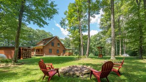 A cabin with a fire pit and Adirondack chairs in a wooded area. - Cozy Dog Friendly Cabin Near State Park w/ Hot Tub (Oakland)