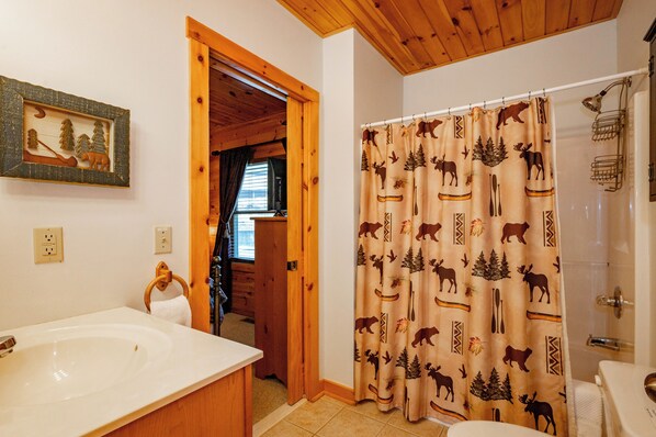 Un baño con una bañera grande, un lavamanos y una cortina de ducha con estampado de animales.