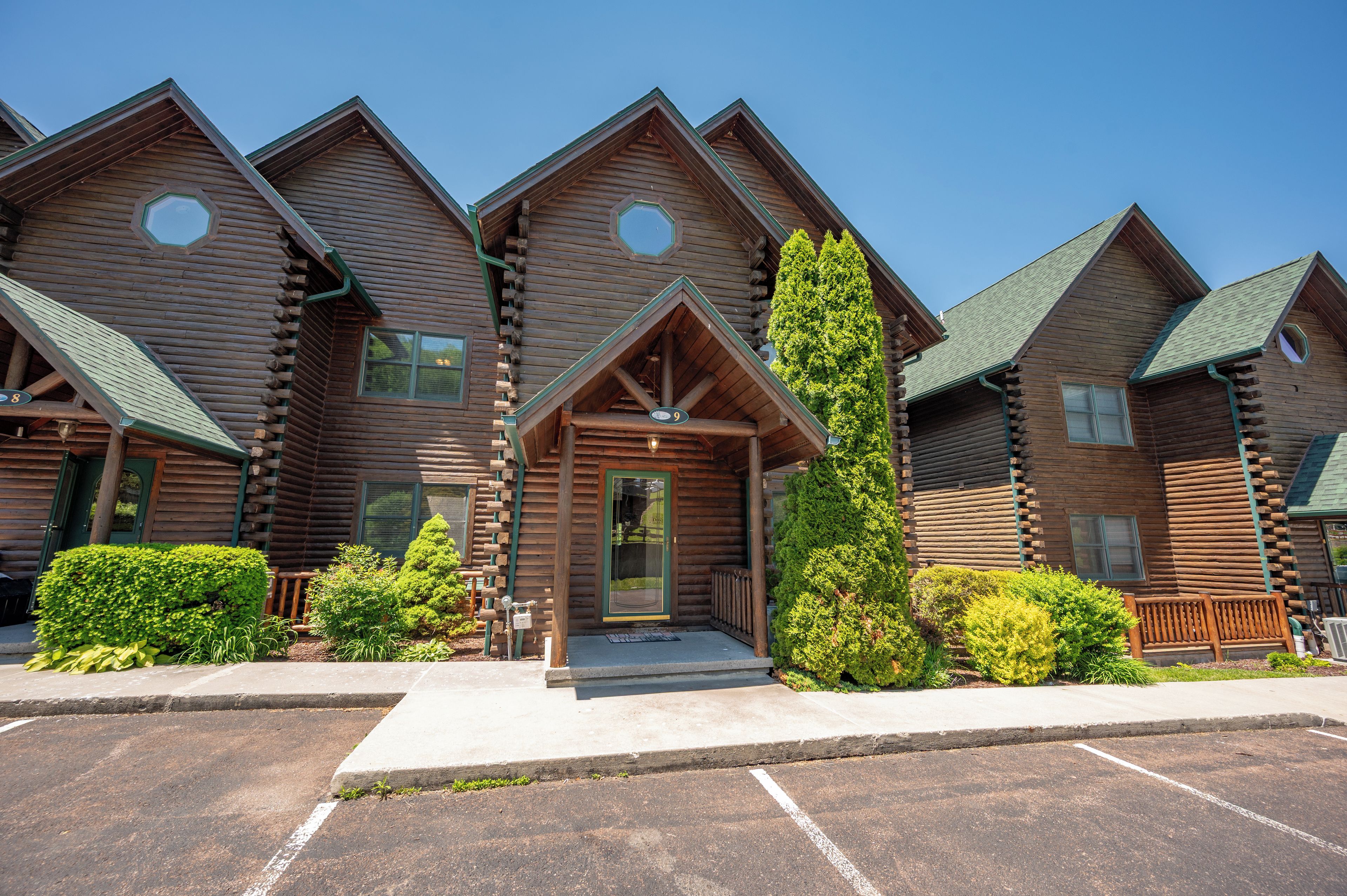 A row of log cabin-style buildings with a central entrance featuring a porch and a door.
