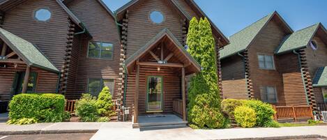 A row of log cabin-style buildings with a central entrance featuring a porch and a door.