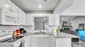 A modern kitchen with white cabinetry, a granite countertop, and a built-in oven. - Sweetwater · Sweetwater home in Heart of Mandarin (Jacksonville)