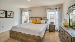 A bedroom with a wooden bed, white bedding, a nightstand, a dresser, and a mirror.