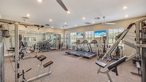 A gym with treadmills, weight machines, and a mirror wall.