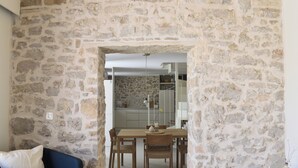 Ein Zimmer mit Steinwänden, einem Esstisch mit Stühlen, einer Couch und einem kleinen Tisch mit einer Vase.