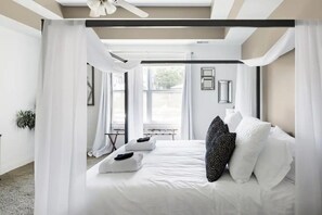 Ein modernes Schlafzimmer mit einem großen Bett, weißer Bettwäsche und einem Baldachin.