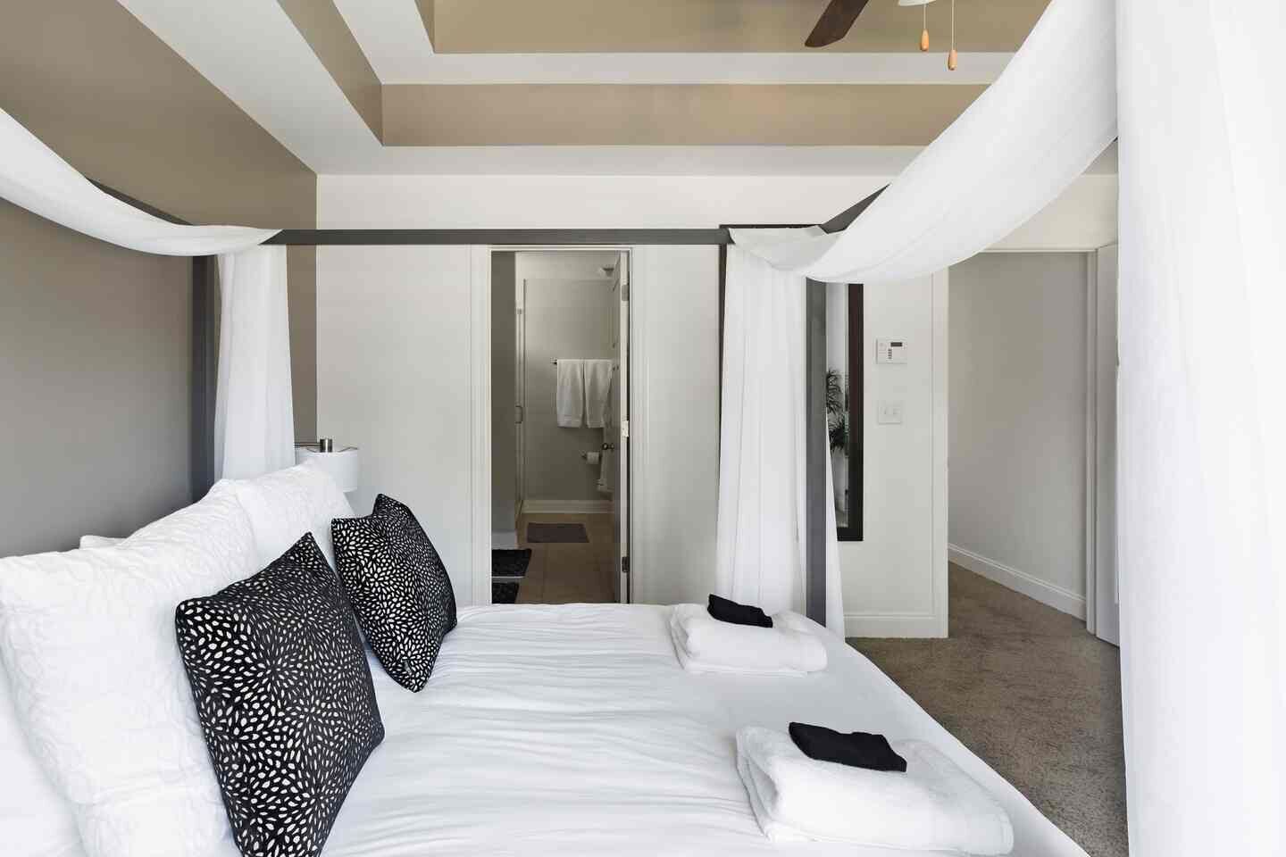A modern hotel room with a large bed, a walk-in closet, and a view of the bathroom.