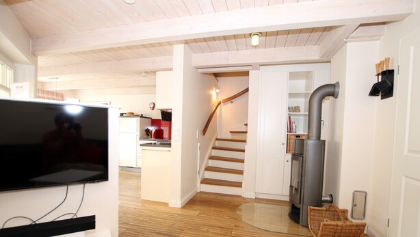 A modern kitchen with wooden flooring, a built-in stove, and a dining area with a glass table. - 5-star vacation home with approx. 80 sqm living space on the ground and upper floor (Wyk auf Föhr)