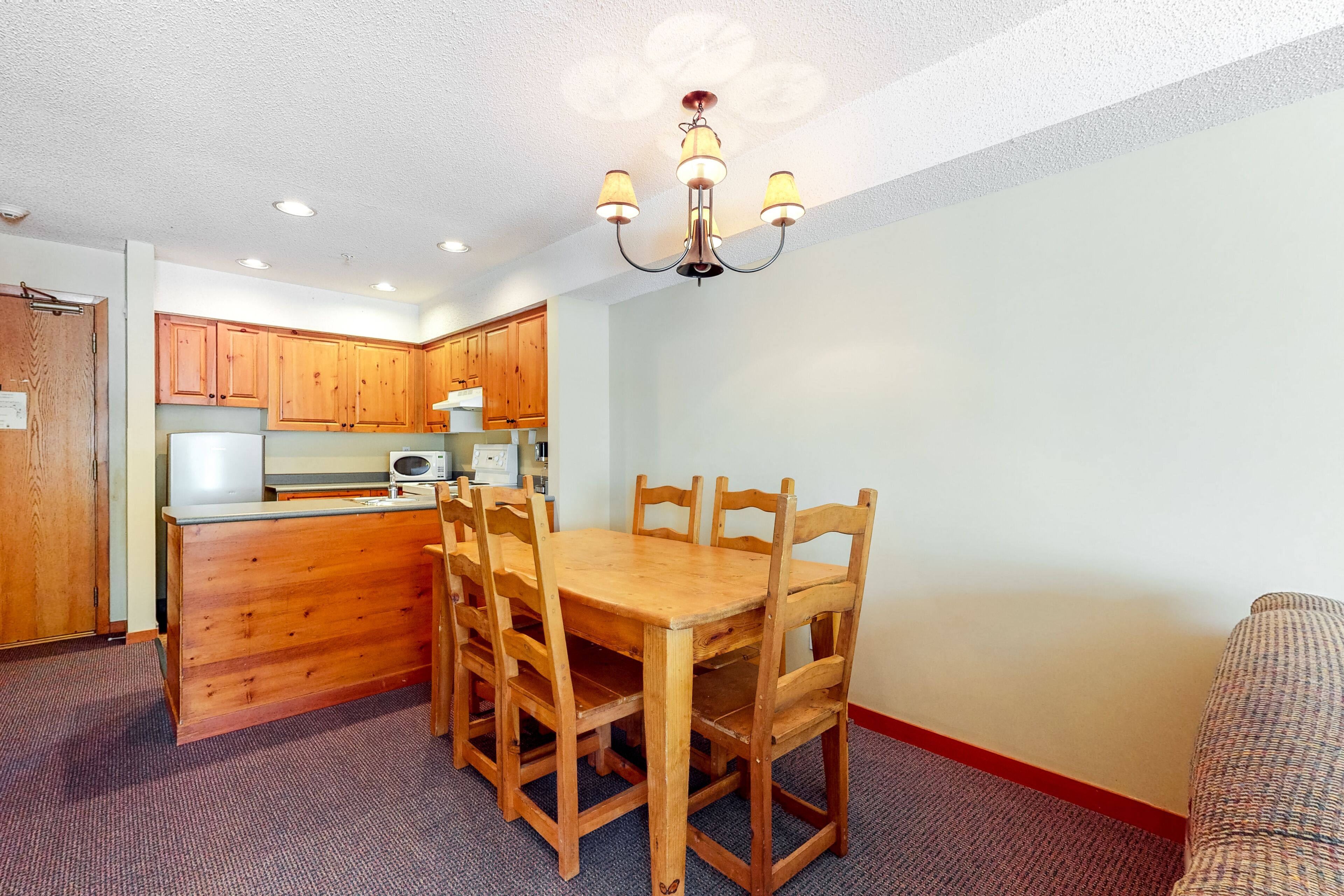 A compact kitchen with wooden cabinets, a dining table, and chairs.