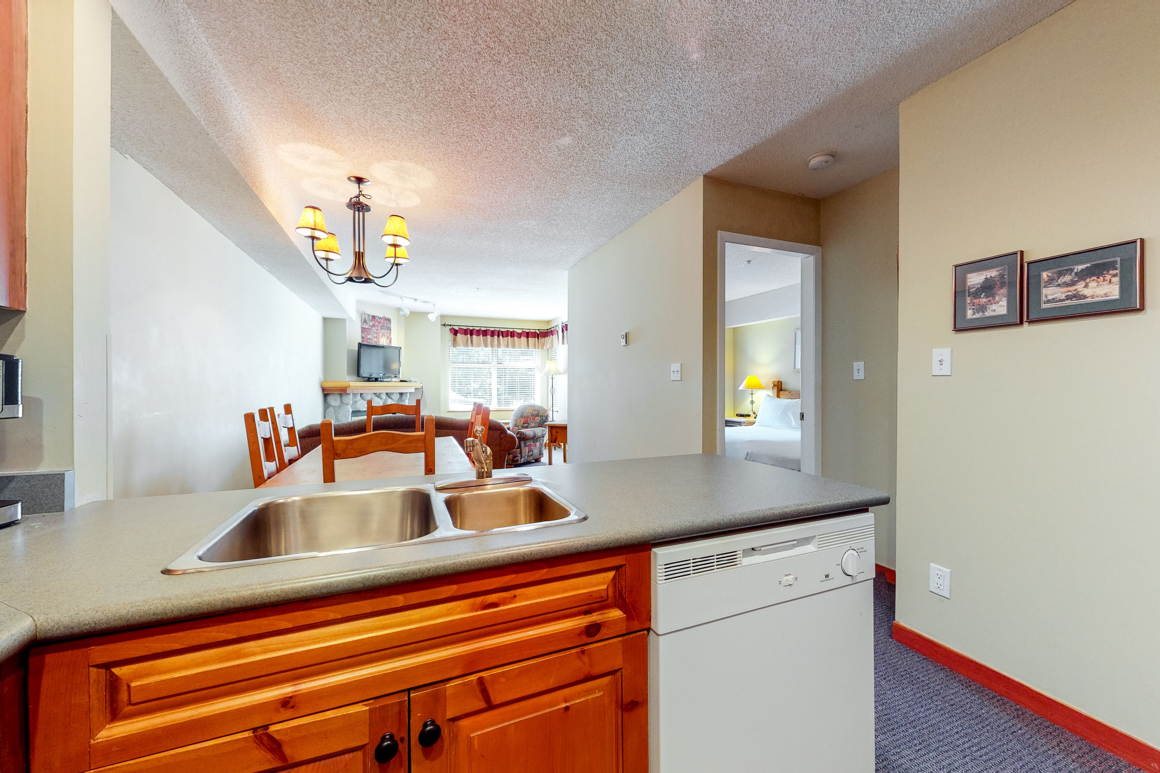 A kitchen with wooden cabinets, a double sink, and a built-in dishwasher.