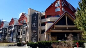 A row of multi-story buildings with a prominent red and beige color scheme, including a building labeled "LAKE PLACID LODGE". - Lake Placid Lodge by Whistler Premier (Whistler)