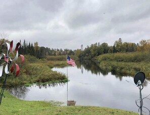 Ein ruhiger See mit einer amerikanischen Flagge, umgeben von Bäumen und einer grünen Wiese.