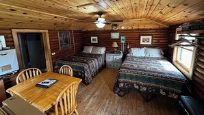 A cabin with two beds, a dining table, and a ceiling fan.
