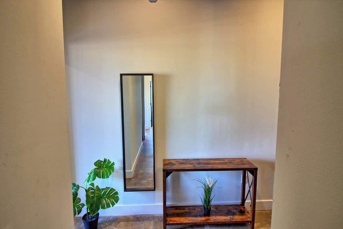 A hallway with a mirror, a wooden console table, and a potted plant.