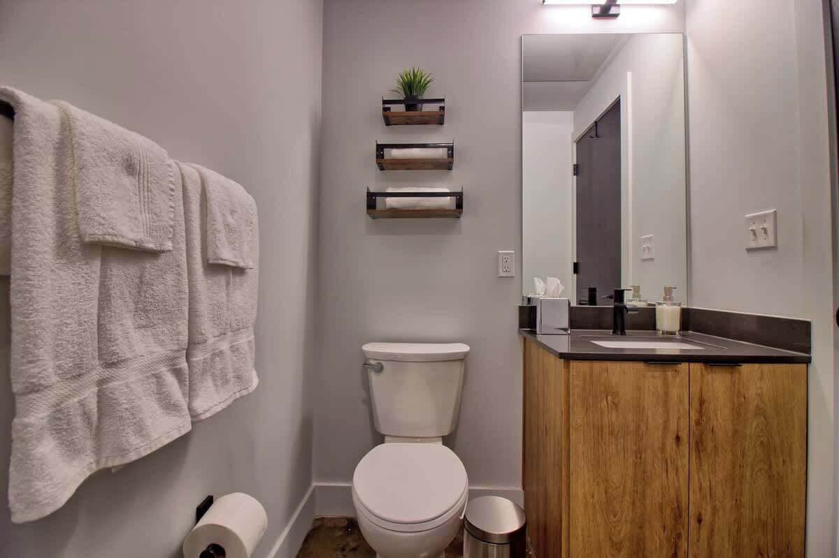 Een badkamer met toilet, wastafel, spiegel en handdoekhouder.