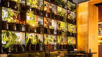 Un espace salon accueillant, agrémenté d’un mur de plantes en pot, de touches de bois et d’un design moderne.