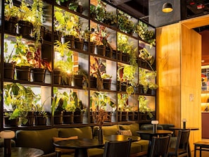 Un espace salon accueillant, agrémenté d’un mur de plantes en pot, de touches de bois et d’un design moderne.