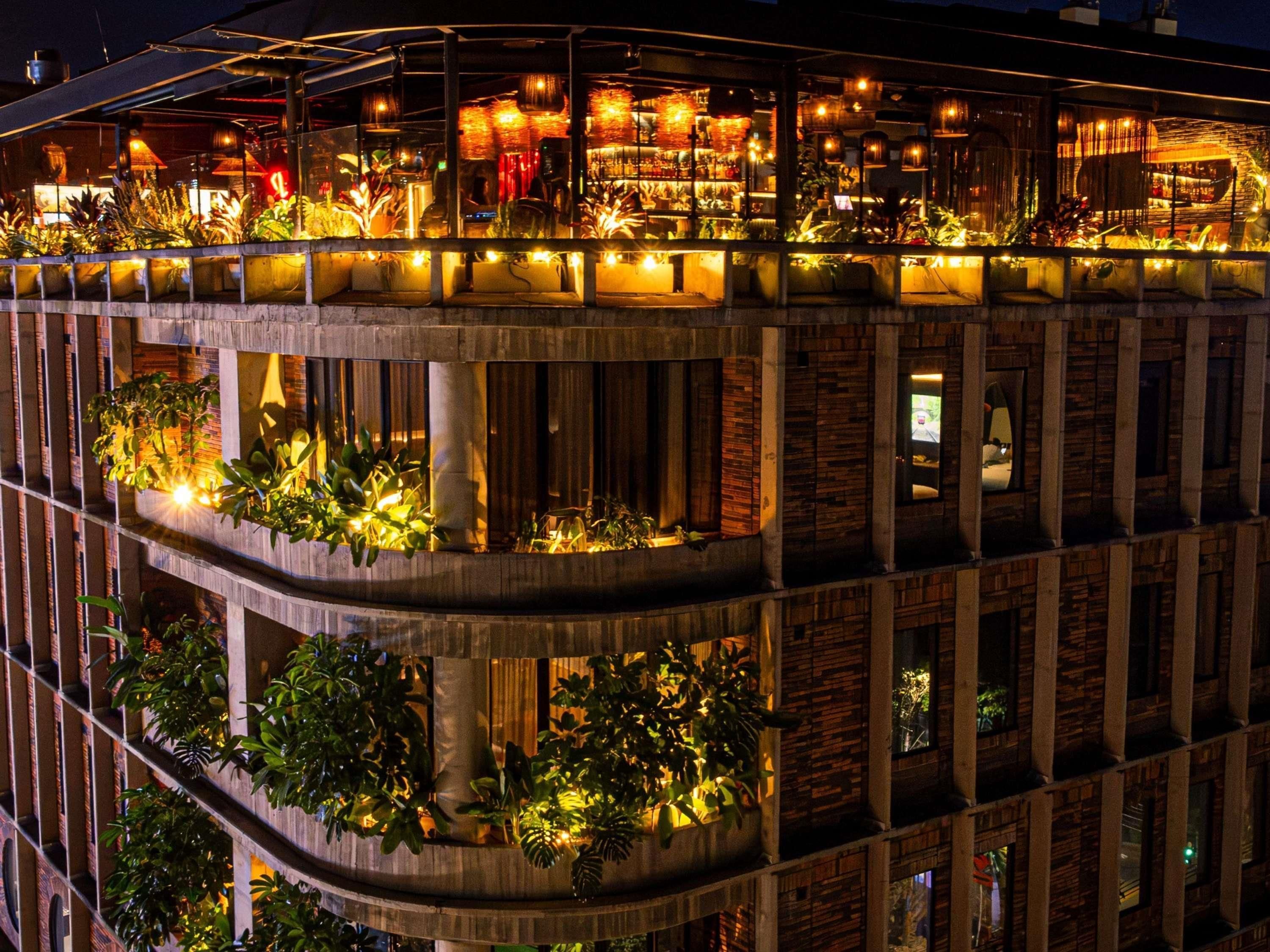 A multi-story building with balconies, outdoor seating, and plants.
