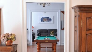 Une table de billard dans une pièce dotée d’une bibliothèque en bois et d’une œuvre d’art encadrée accrochée au mur.