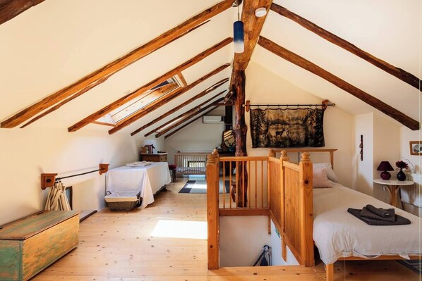 A cozy attic bedroom with exposed wooden beams, a loft bed, and a rustic aesthetic.