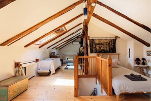 Une chambre mansardée chaleureuse avec des poutres apparentes, un lit en mezzanine et une esthétique rustique.