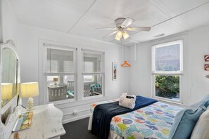 A bedroom with a bed, a dresser, a mirror, a ceiling fan, and two windows with blinds. - Oceanfront Getaway - Private Boardwalk, Enclosed sun porch (Folly Beach)