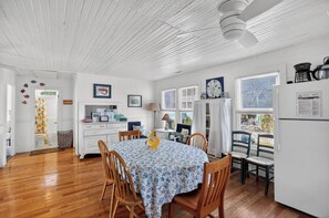 A dining area with a table covered in a floral tablecloth, surrounded by wooden chairs. - Oceanfront Getaway - Private Boardwalk, Enclosed sun porch (Folly Beach)