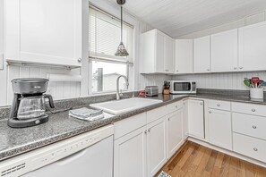 Enjoy cooking in this well-equipped kitchen with a granite countertop, white cabinetry, and stainless steel appliances.