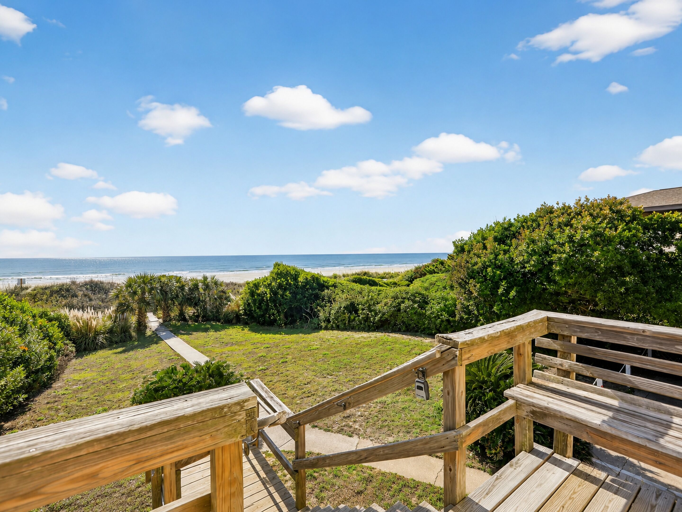 A wooden deck with a view of the beach and ocean.