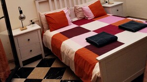 A neatly made bed with a checkered bedspread, two bedside lamps, a nightstand with a drawer, and a black and white checkered floor. - Luxury Villa With Private Pool heated pool FREE, And Garden, WIFI FREE (Yaiza)