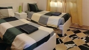 A hotel room with two beds, a nightstand, a lamp, and a checkered floor. - Luxury Villa With Private Pool heated pool FREE, And Garden, WIFI FREE (Yaiza)