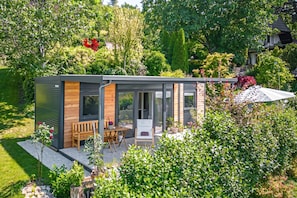 A modern house with a patio, a wooden table, and chairs.