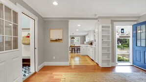A spacious hallway with wooden flooring, white cabinetry, and a blue door leading outside. - Family friendly home in heart of Cape Porpoise (Kennebunkport)