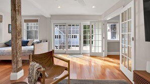 A spacious room with a large window, a ceiling fan, and a wooden floor. - Family friendly home in heart of Cape Porpoise (Kennebunkport)
