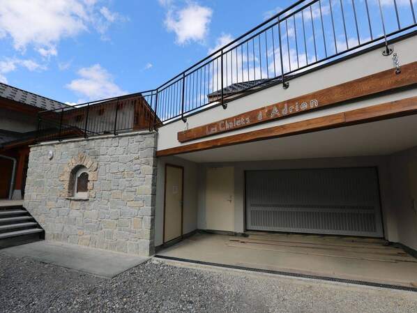 A building with a stone facade, a wooden upper floor, and a sign reading "Les Chalets d'Adria".