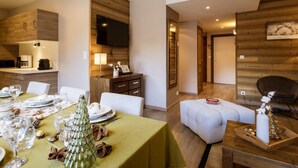 A modern living room with a dining area, wooden paneling, a flat-screen TV, and a cozy seating arrangement. - 4-room apartment, 8 people, pets allowed, terrace (Valloire)