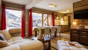 A spacious living room with a sofa set, dining area, kitchen, and a large TV. - 4-room apartment, 8 people, pets allowed, terrace (Valloire)