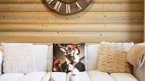 A cozy living room with a wooden wall clock, a white sofa, a decorative pillow, a small Christmas tree, and a candle holder. - 4-room apartment, 8 people, pets allowed, terrace (Valloire)