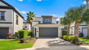 A modern two-story house with a garage, surrounded by well-maintained landscaping including palm trees and shrubs. - Liberty Hope: Private Pool, Water Park, Golf View, Near Disney (Kissimmee)
