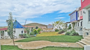 Zona residencial con un césped cuidado, un molino de viento y casas con fachadas coloridas.