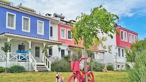 Una hilera de casas coloridas con un patio césped y una bicicleta roja.