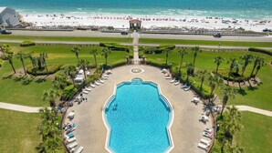 An aerial view of a resort with a central swimming pool, surrounded by palm trees and lounge chairs, with a beach and ocean in the background. - The ONLY 1 Bedroom with a private Bunk Room - Beach Service Included!!! (Miramar Beach)