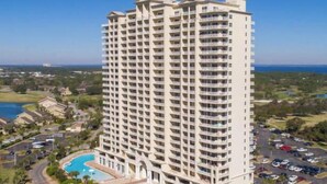 Un hôtel de grande hauteur doté de nombreux balcons, d’une piscine et d’un parking.