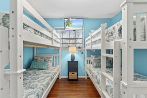 Cozy nautical-themed room with two beds, a bedside table, and a wall-mounted TV.