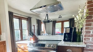 Una cocina con estufa de acero inoxidable, armarios de madera y una pared de ladrillo decorativa.