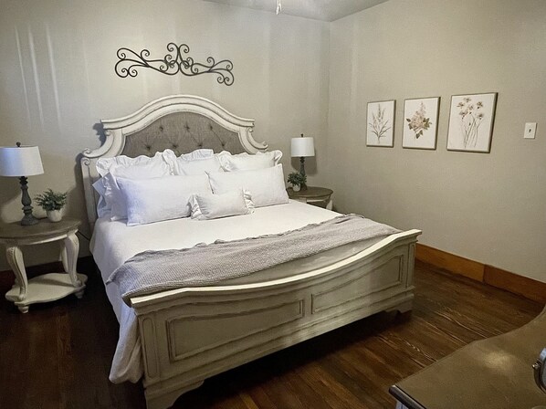 A neatly made bed with a headboard, two bedside tables with lamps, and three framed botanical prints on the wall. - Beautiful Craftsman Style Home; Peaceful backyard; Close to Main (Fredericksburg)