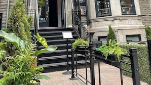 Un edificio histórico con fachada de piedra, una escalera de metal negro y un letrero que indica un restaurante.