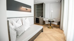 Una habitación de hotel moderna con sofá, una mesita, una lámpara y un minibar.