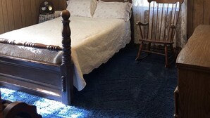 A bedroom with a wooden bed, a rocking chair, a ceiling fan, and a window with curtains.